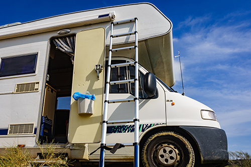 mobile home with ladder against a blue sky